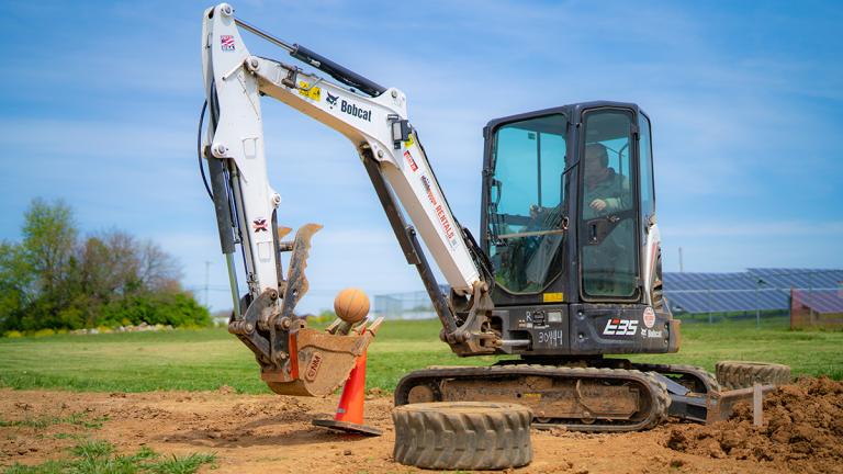 A person attempting to play basketball with a Bobcat Backhoe