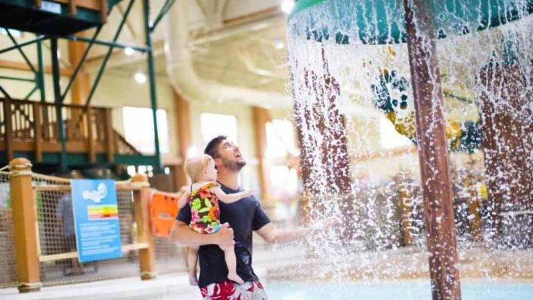 Father holds his daughter while in the Cub Paw Pool.