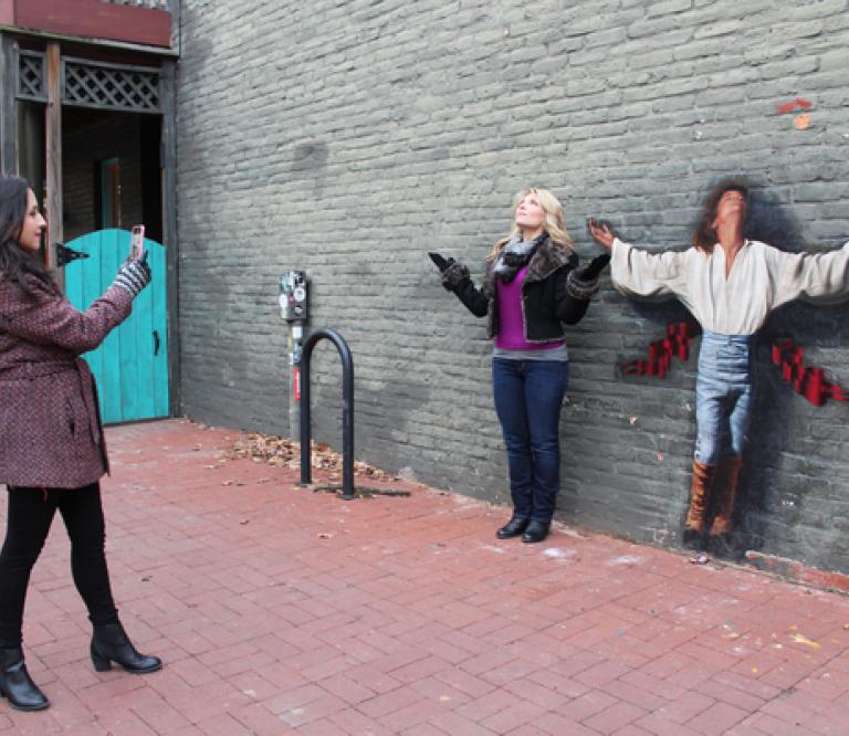 Frederick Visitor Taking Photo Next to Wall Mural